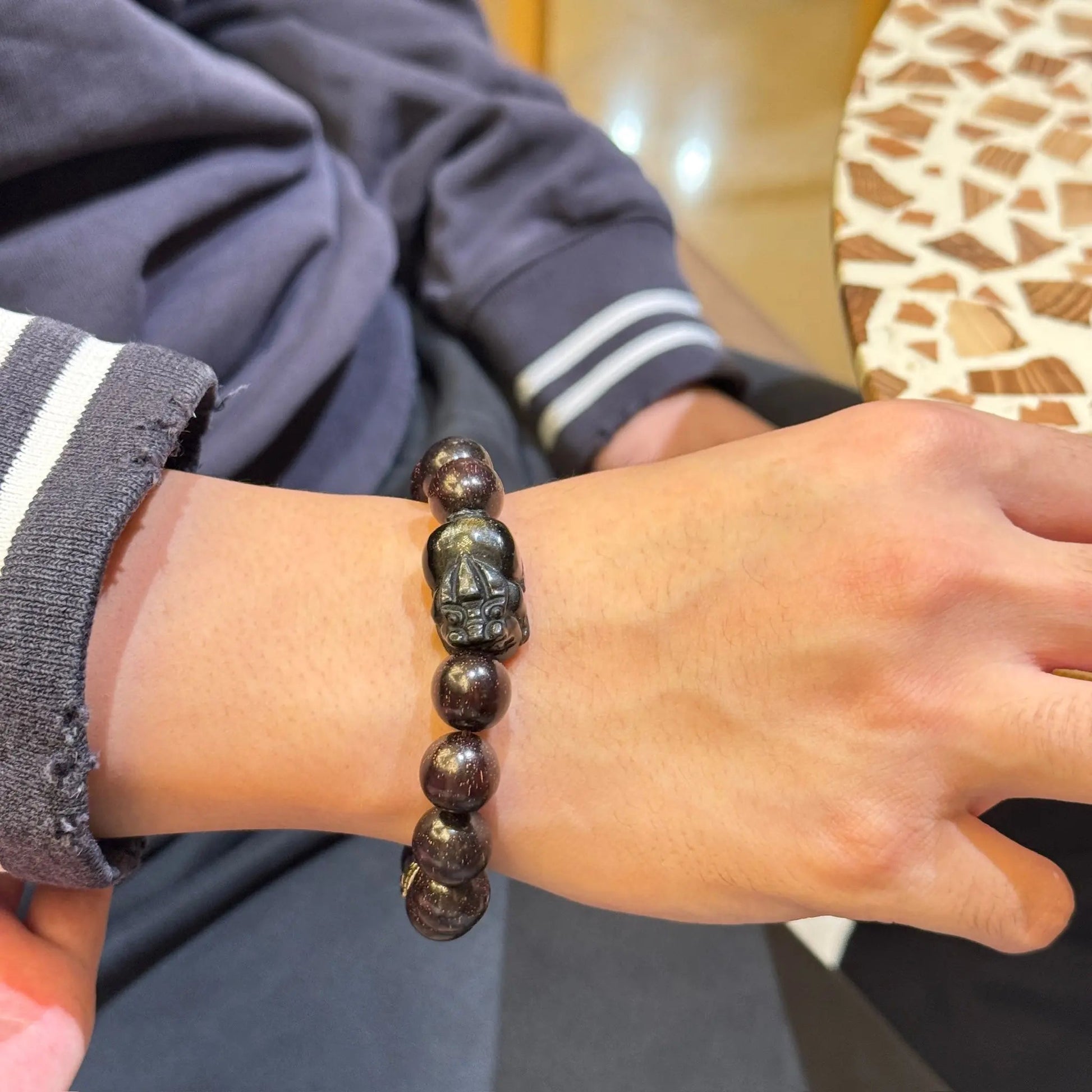 Men’s sandalwood bracelet with obsidian charm on model's wrist, showcasing golden obsidian pixiu and zodiac beads.
