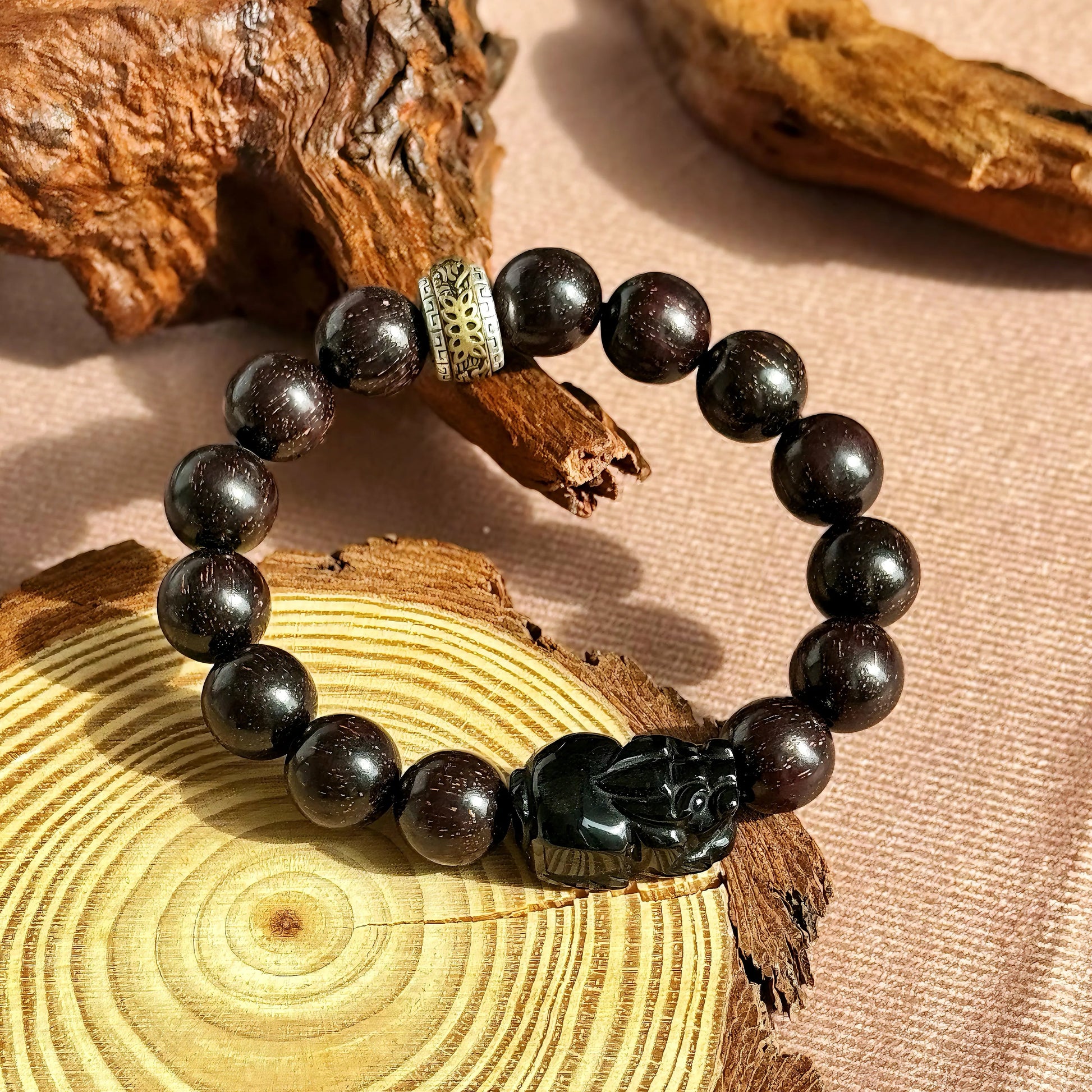 Men’s sandalwood bracelet with obsidian charm featuring zodiac beads on a wooden background.