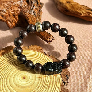 Men’s sandalwood bracelet with obsidian charm featuring zodiac beads on a wooden background.