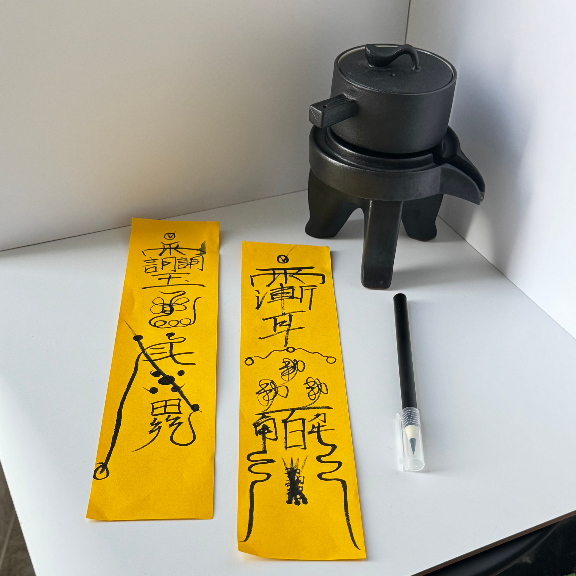 Two yellow strips with black text and a black pen on a white surface.