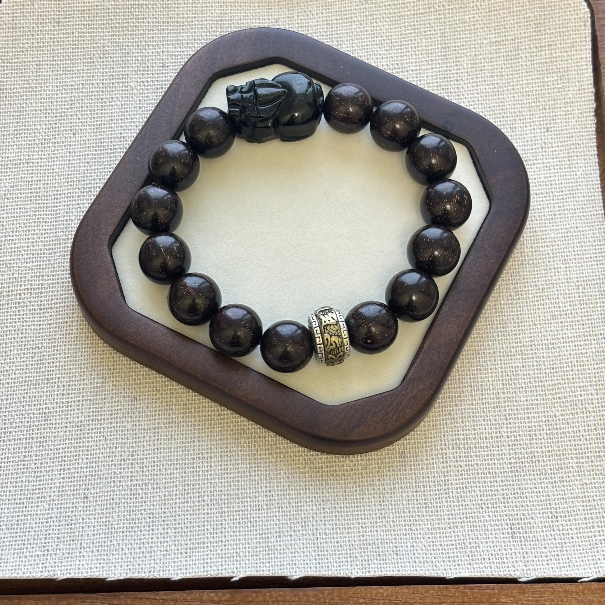 Men’s sandalwood bracelet with obsidian charm featuring black beads and a unique charm on display.