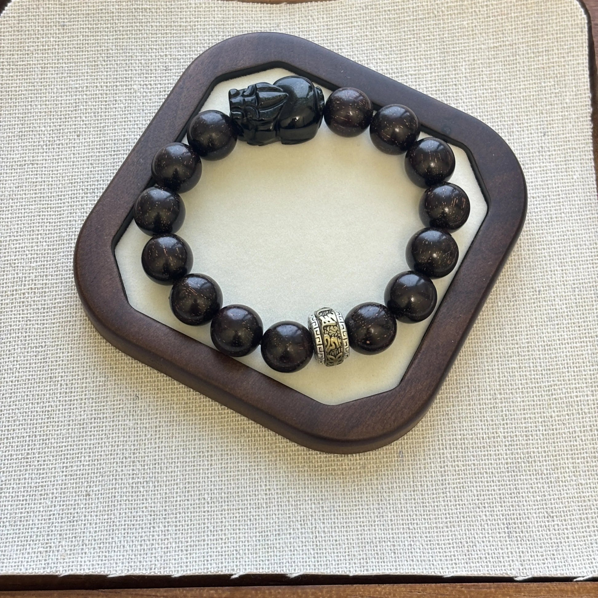 Men’s sandalwood bracelet with obsidian charm featuring a unique Pixiu design on a stylish display.