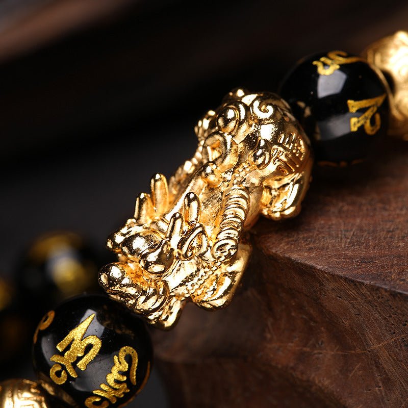 Close view of the gold Pixiu charm on the black obsidian bracelet